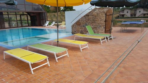 a pool with four lounge chairs and an umbrella at B&B Podere Montese in Villafranca in Lunigiana