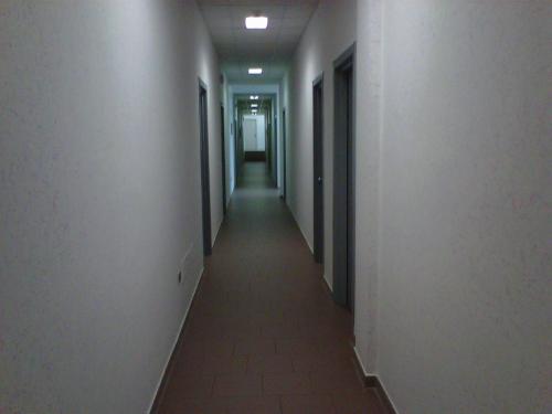 an empty hallway with white walls and a long corridor at Hostiliae Ciminiera Hotel in Ostiglia