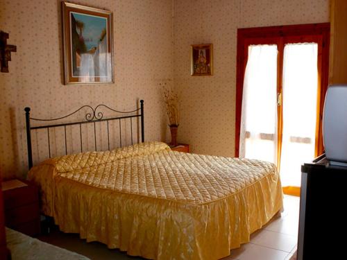 a bedroom with a bed with a yellow bedspread and a window at Cantina del Casale in Tramonti
