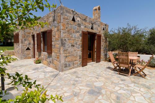 a stone building with a table and a chair on a patio at Athena Villas Olive Grove & Estate in Gouves