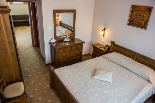 ein Schlafzimmer mit einem Bett, einem Spiegel und einer Kommode in der Unterkunft Complex Casa Lux in Botoşani
