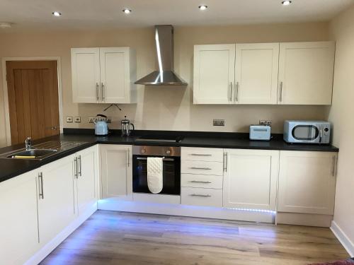 a kitchen with white cabinets and a sink and a microwave at The Cothi Bridge Apartments in Carmarthen