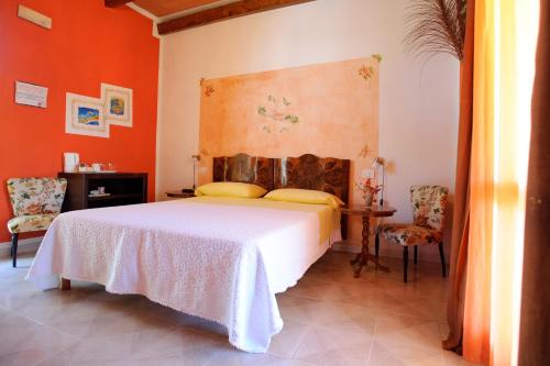 a bedroom with a white bed and orange walls at Hotel Villa Belfiori in Torre Dei Corsari