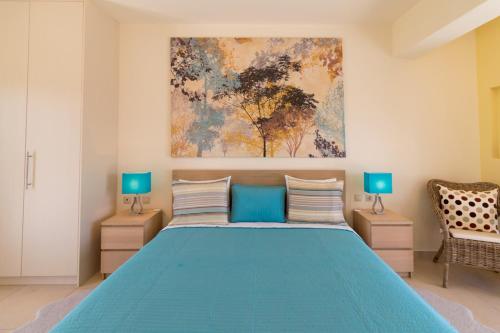 a bedroom with a blue bed and a painting on the wall at Athena Villas Olive Grove & Estate in Gouves