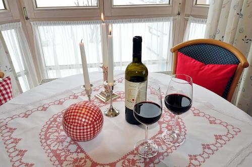 a bottle of wine and two glasses on a table at Gemütliche Ferienwohnung Bergwiese, 2-Raum, separates Schlafzimmer, schönen Balkon oder Terrasse, Komfort Ausstattung, ruhige Südlage, kostenfrei WLAN und schöne helle Sauna, Brötchenservice, Parkplatz, Hunde auf Anfrage, E-Tankstelle, Sonnenlage in Balderschwang