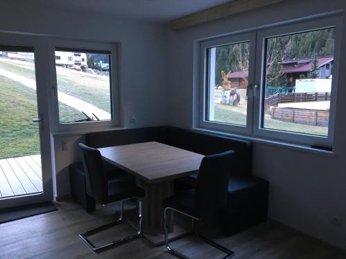 a dining room with a table and two windows at Haus Bergheim in Sankt Leonhard im Pitztal