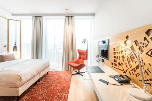 a hotel room with a bed, chair, mirror and window at Capri by Fraser Berlin in Berlin