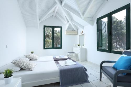 a white bedroom with a bed and a chair at The Pines in Skala