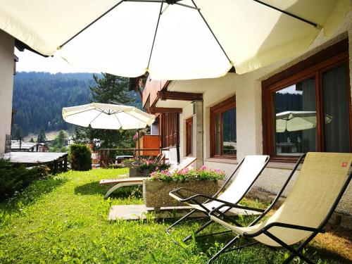 a couple of chairs and umbrellas sitting outside of a house at Style Hotel Grifone in Madonna di Campiglio