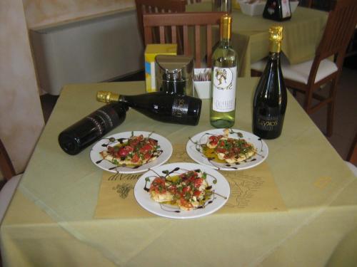 uma mesa com três pratos de comida e uma garrafa de vinho em Hostiliae Ciminiera Hotel em Ostiglia