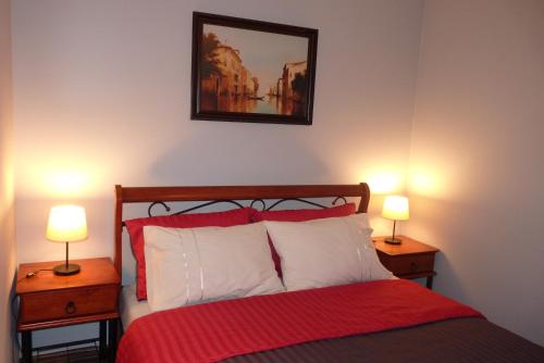 a bedroom with a red bed with two lamps on tables at Apartament Młyńska in Zamość