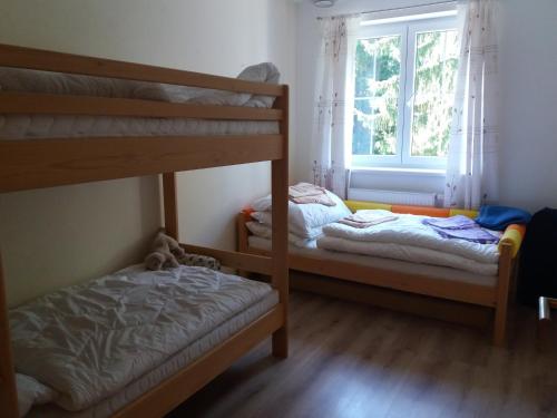 2 łóżka piętrowe w pokoju z oknem w obiekcie Apartmán Špičák Sruby w mieście Špičák