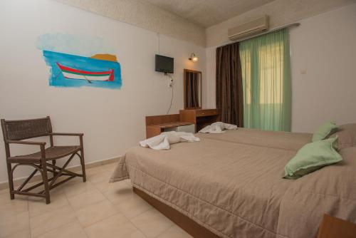 a hotel room with two beds and a chair at Fragiskos Hotel in Matala