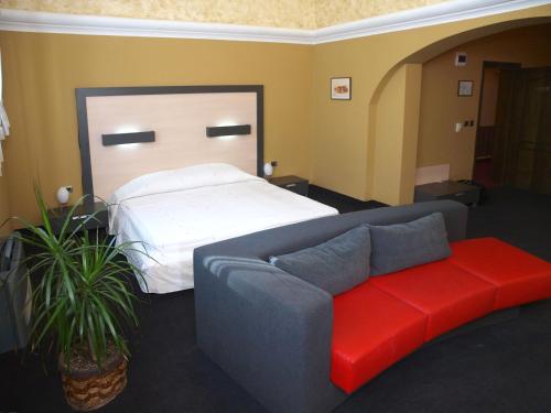 a bedroom with a bed and a couch with a red bench at Семеен хотел Анна-Кристина in Vidin