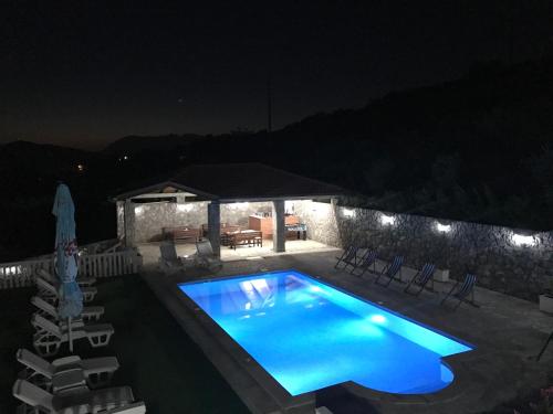 a swimming pool at night with chairs around it at Apartments Vila Lazarevic in Tivat