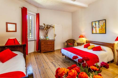 a bedroom with two beds with red sheets and flowers at Logis Hôtel Restaurant des Corbières in Lagrasse