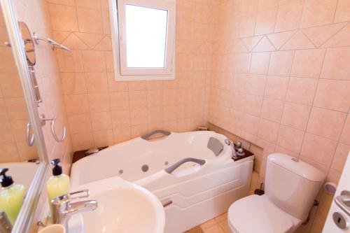 La salle de bains est pourvue d'une baignoire, de toilettes et d'un lavabo. dans l'établissement Athena Villas Olive Grove & Estate, à Gouves