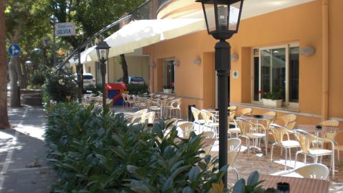 a street light in front of a building with tables and chairs at Hotel Silvia in Misano Adriatico