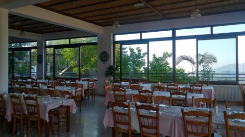 a dining room with tables and chairs and windows at Two Flowers Hotel in Pedoulas