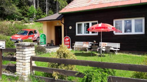 a house with a red umbrella and a table and chairs at Chata Javorina in Javorník