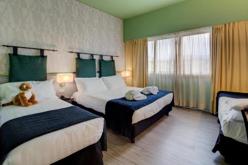 una camera d'albergo con due letti e un orsacchiotto sopra di Best Western Plus CHC Florence a Firenze
