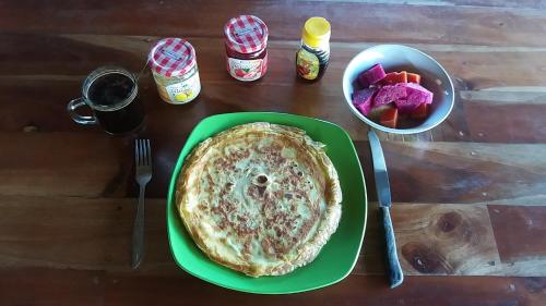 a green plate with a pie on top of a table at Sadati Home Stay in Batukaras
