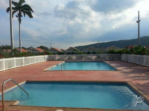 a swimming pool in a yard next to a fence at Caymanas Estate beautiful three bedroom house in Spanish Town