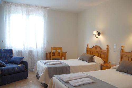 a hotel room with two beds and a blue couch at Hostal El Paso in Beranga