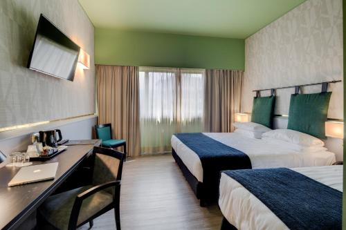 a hotel room with two beds and a desk at Best Western Plus CHC Florence in Florence