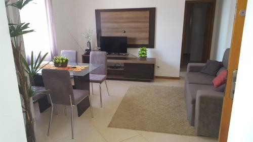 a living room with a table and a couch and a television at Tramandaí Sunrise Residence in Tramandaí