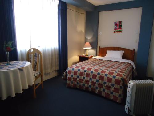 a hotel room with a bed and a table and a window at Hotel T'ika in Puno