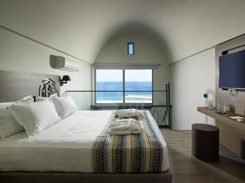 a bedroom with a bed with a view of the ocean at Kakkos Beach Hotel - Adults Only in Ierápetra