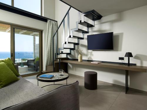 a living room with a staircase with a tv at Kakkos Beach Hotel - Adults Only in Ierápetra