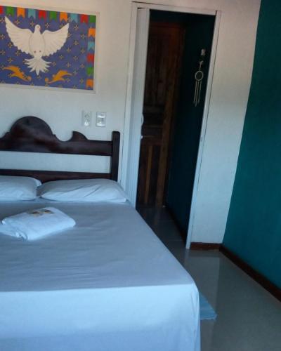 a bedroom with a white bed with an angel painting on the wall at SunriseBelaVista Pousada e Flats in Paraty