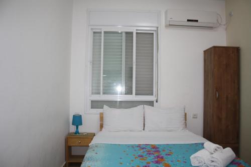 a small bedroom with a bed with a window at Ga'aton Motel in Nahariyya