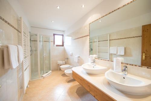 a bathroom with two sinks and a shower at Hotel Jager Hans in San Martino