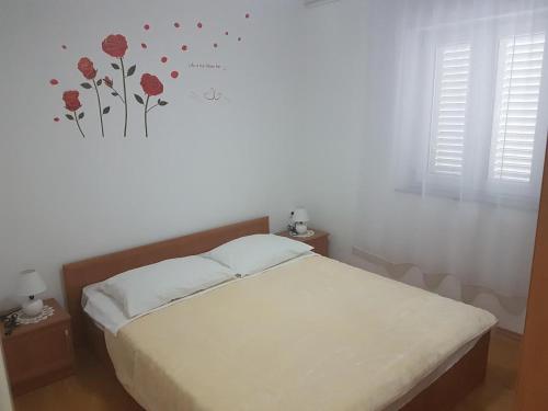 a bedroom with a bed with red flowers on the wall at Apartment Crikvenica 6 in Crikvenica