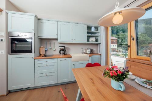 a kitchen with white cabinets and a wooden table at Bio- und Vitalbauernhof Bacherhof in Millstatt