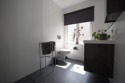 Un baño blanco con inodoro y ventana. en Sack-Time fashion boutique hotel 1 & 2, en Zandvoort