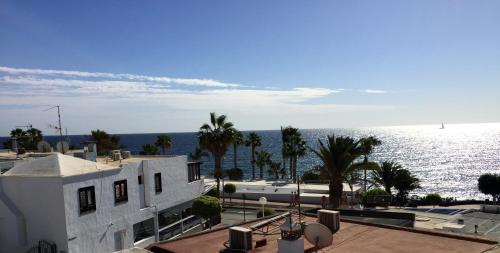 a white building with the ocean in the background at Apartamento Verena in Puerto del Carmen