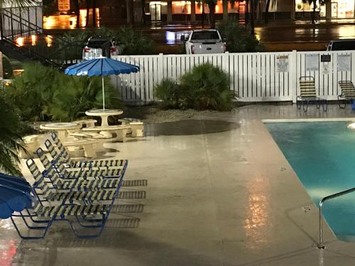 a pool with chairs and a table and an umbrella at Stay Inn - Bartow in Bartow