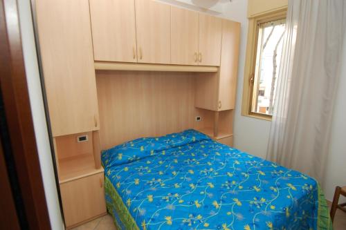 una piccola camera da letto con un letto con una coperta blu di Apartments in Rosolina Mare 24870 a Rosolina Mare