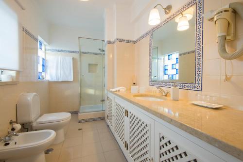 a bathroom with a sink and a toilet and a mirror at Villa Eira in Vila Nova de Milfontes
