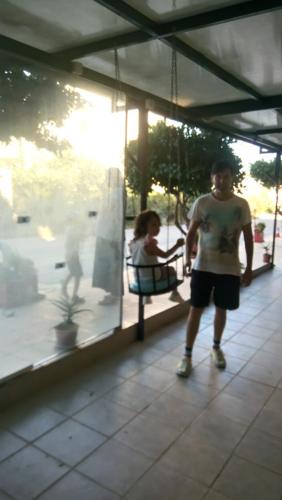 a young boy standing next to a child in a swing at Villa George - Family Holidays in Nea Makri