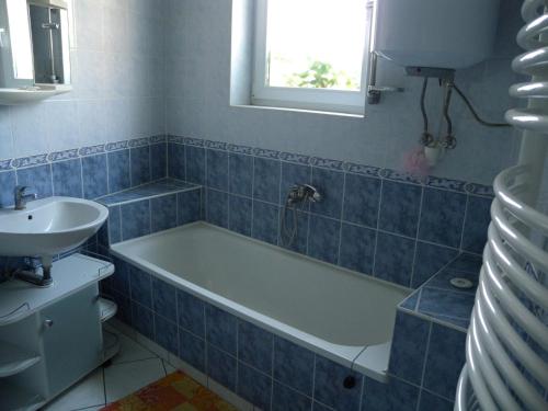 a blue tiled bathroom with a tub and a sink at Apartment Balatonkeresztur/Balaton 19286 in Balatonkeresztúr