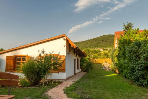 a white house with a garden and a hill in the background at Hajnalka Apartment in Badacsonytomaj