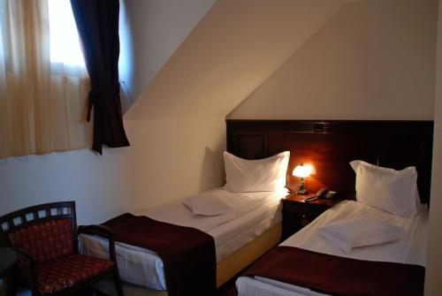 a bedroom with two beds and a chair and a window at Hanul Domnesc in Braşov