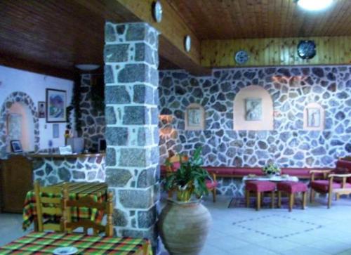a room with a stone wall and a table and chairs at Atlantis Hotel in Myrties