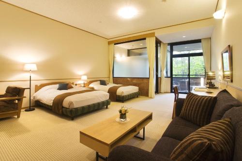 高山市にある中尾高原ホテル 風車のベッド2台とソファが備わるホテルルームです。