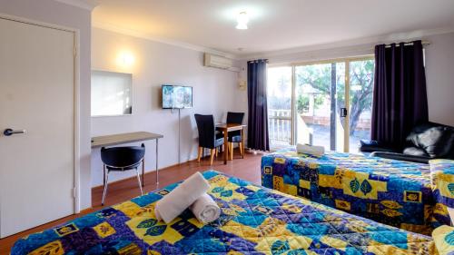 Habitación de hotel con cama, mesa y escritorio. en Australind Tourist Park en Australind